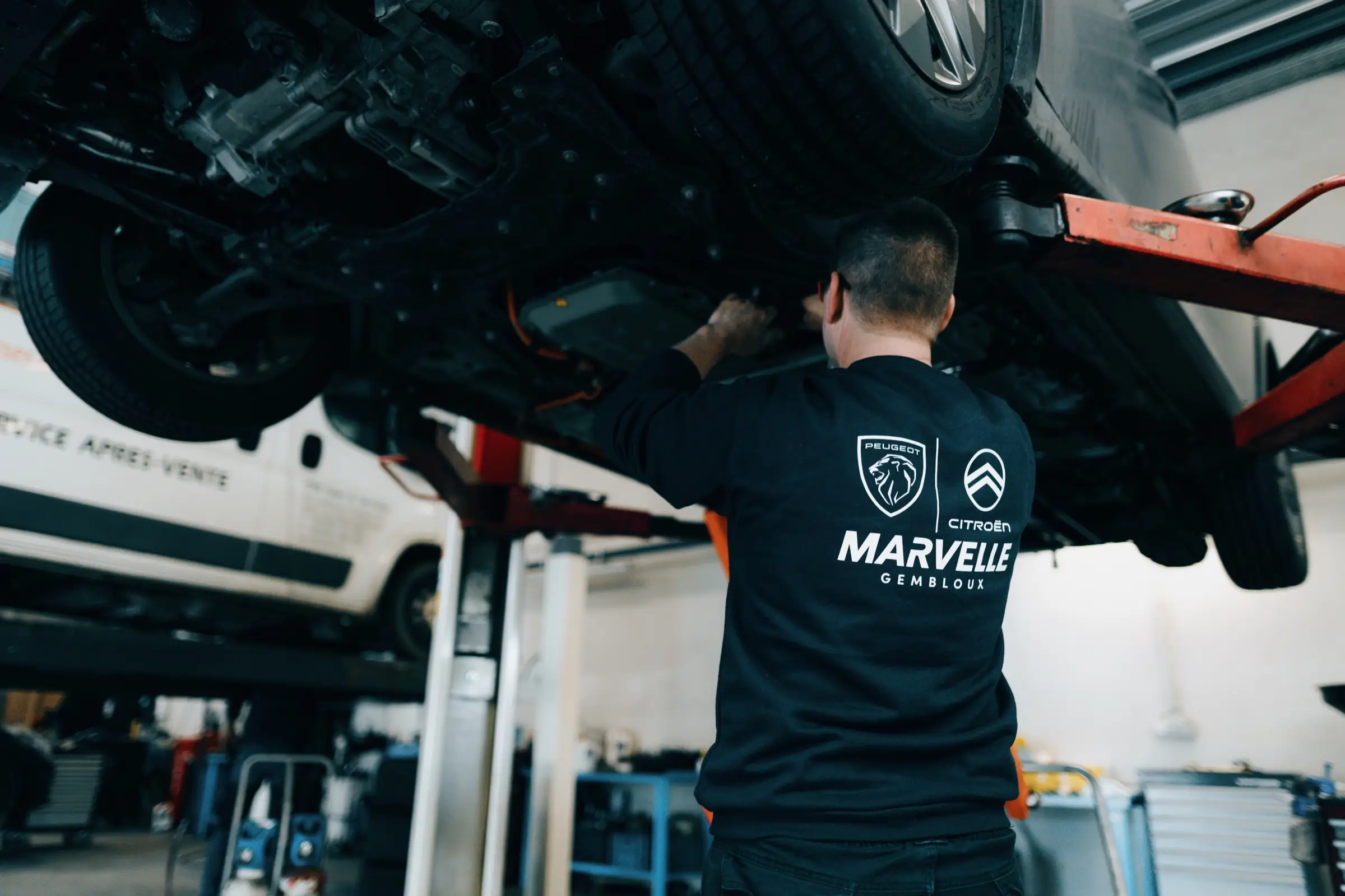 Mécanicien Marvelle Automobile travaillant sous un véhicule sur pont